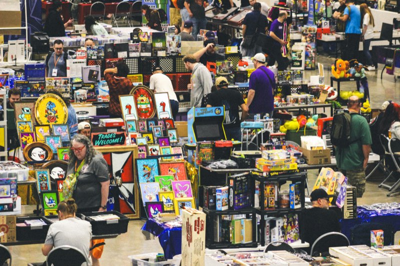 A busy indoor market with tables of used games, art and collectibles