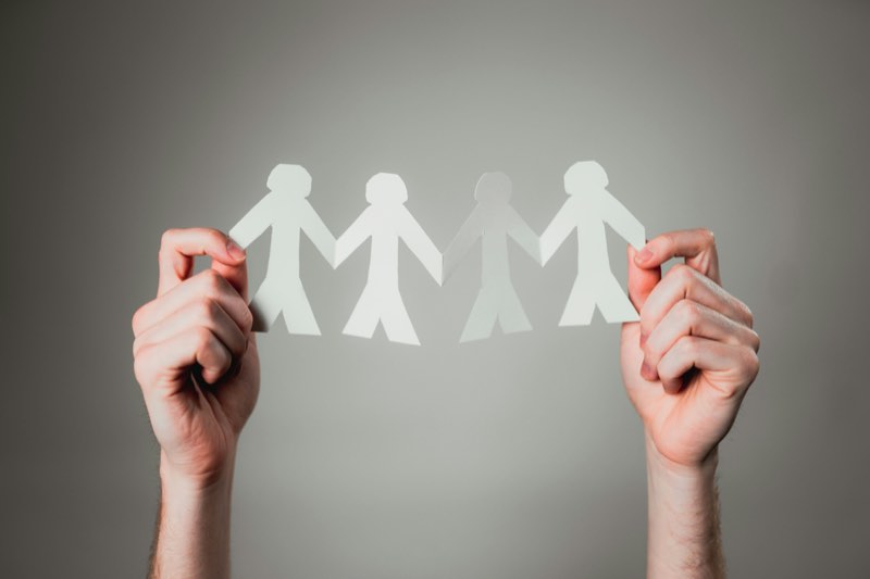 Two hands holding up a paper chain of people